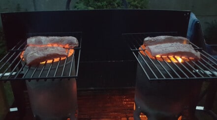 Afterburner steak grilling on top of two charcoal chimneys.