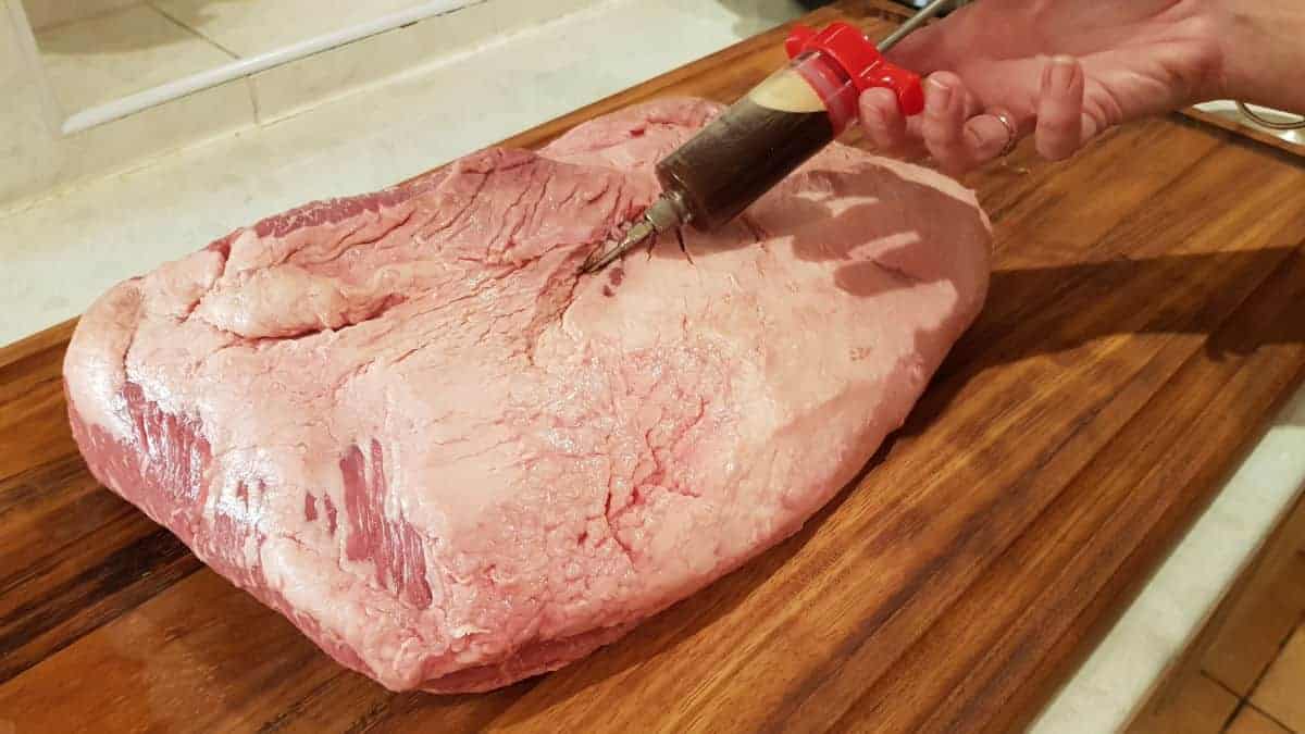 A full packer brisket being injected with a marin.